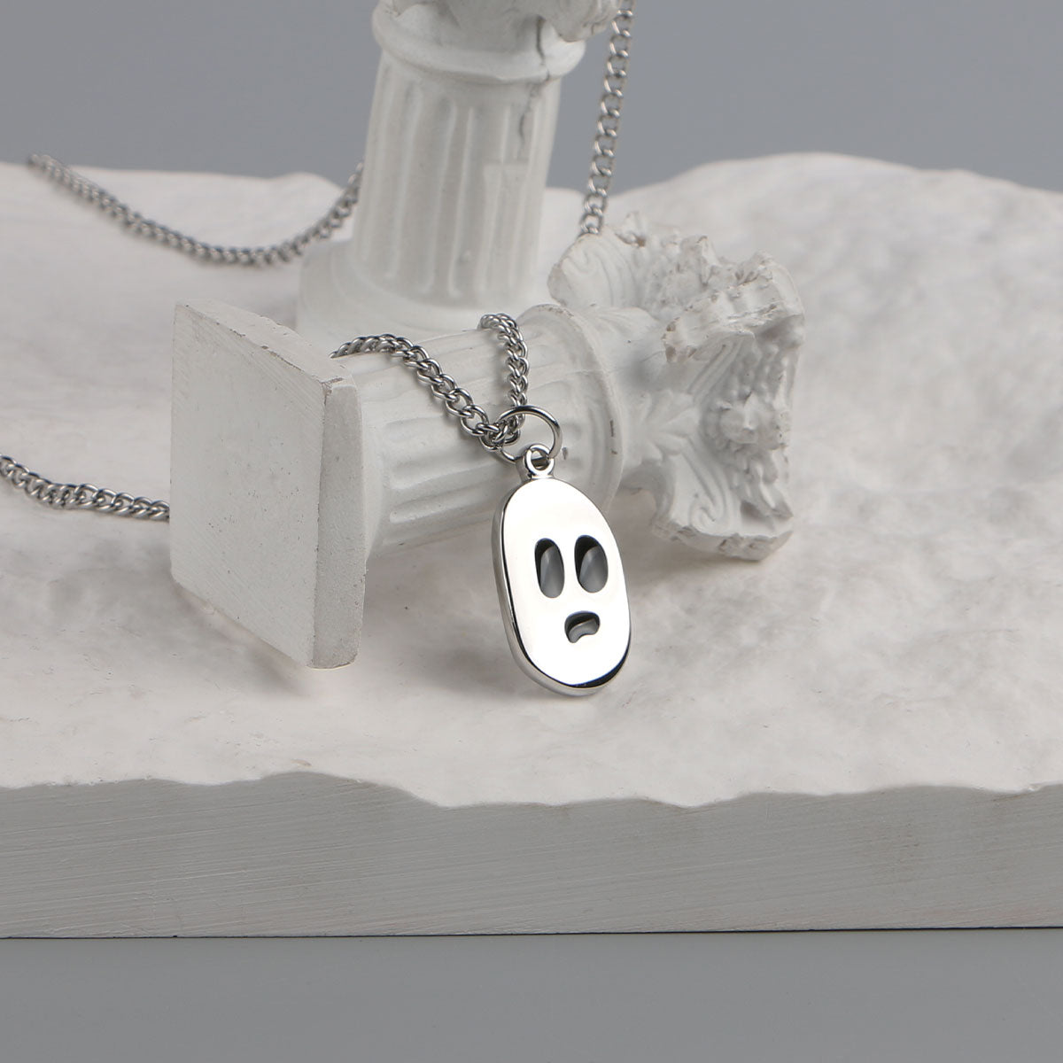 Ghost face pendant necklace displayed on white props