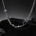 Spider necklace with mixed chain links and star detail against a dark background